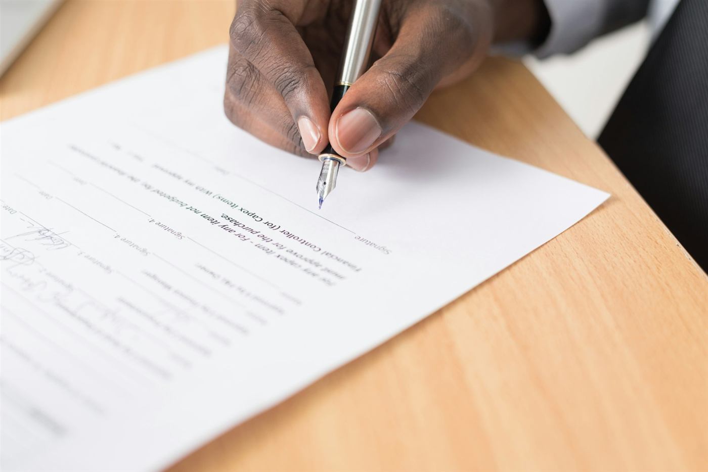 A hand signing a document with a fountain pen